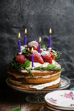A layered strawberry and cream sponge cake decorated with candles