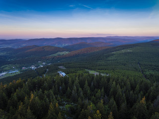 Sunset. Aerial view of the summer time in mountains near Czarna Gora mountain in Poland. Pine tree forest and clouds over blue sky. View from above.