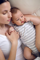 mom with a newborn son lying on a white bed