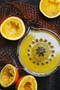 Freshly squeezed orange juice in squeezer surrounded by orange halves 
