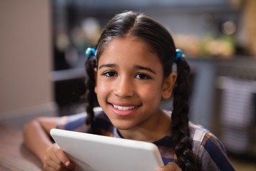 Portrait of girl holding digital tablet at home