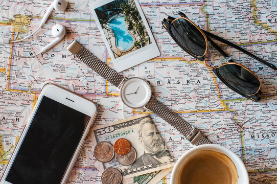 Close-up of smartphone, watch, sunglasses, money, coffee on the map