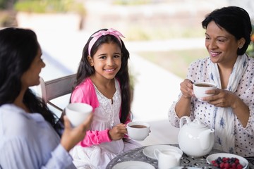 Fototapeta premium Girl having breakfast with mother and grandmother