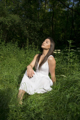 Young girl with white dress posing in a grass field