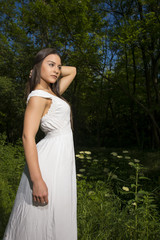 Young girl with white dress posing in a grass field