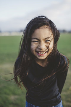 Cute elementary school aged asian girl happy in windy  field 