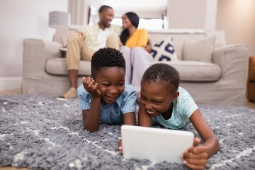 Children using digital tablet while parents siting 