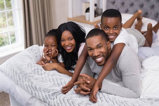 Portrait Of Happy Family Lying Together In Bedroom