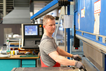 Industriearbeiter arbeitet im Stahlbau an einer Abkantbank für Metallbleche // Industrial worker...