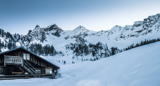 Panorama view to snowcovered big mountains with a alpine cabin in the alps