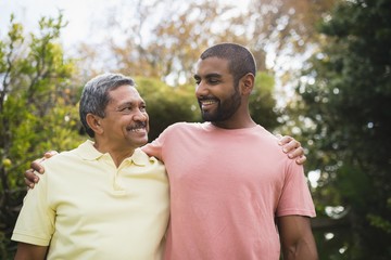 Smiling man looking at his father against trees