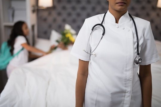 Nurse standing with patient on bed in background