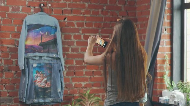 Woman makes a photo of a jeans jacket on a mobile phone. Mobile phone display: a woman is taking pictures on the phone. . Announcement of sale: girl makes a photo of a denim jacket with a picture.