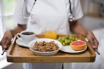 Obraz na płótnie Canvas Mid section of nurse holding breakfast tray