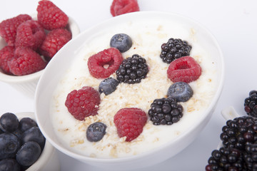 bowl of white yogurt with berries and oat flakes isolated