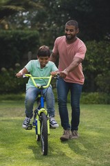 Father assisting son while riding bicycle