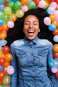 Young african woman playing with many colorful balloons