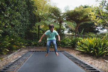 Happy boy jumping on trampoline at park