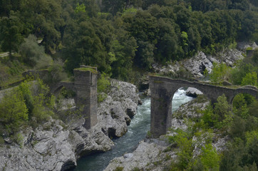 Fototapeta na wymiar Old stone bridge in Golo. View from train carriage window at Kazamozza-Barketta railroad haul (Upper Corsica)