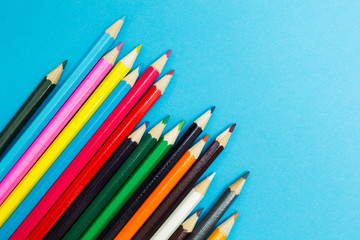 Multicolored pencils on a blue background, children's creativity.