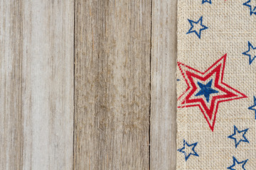 Fototapeta na wymiar USA red and blue stars burlap ribbon on weathered wood background
