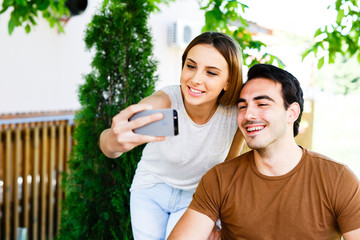 Beutiful couple sitting in caffe and taking selfie with phone