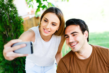 Beutiful couple sitting in caffe and taking selfie with phone