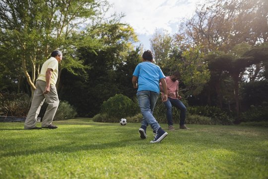 Multi-generation family playing soccer at park