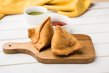 popular indian snack called veg Samosa, favourite tea time snack served with tamarind and mint...