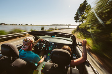 A Happy young couple driving highway 1 in California in their convertible 