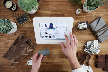 Artisan retail shop small business owners hands ringing up a purchase on digital cash register with products around him