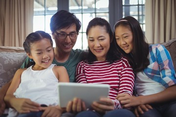 Smiling family using digital tablet together in living room