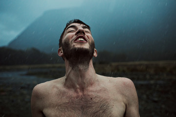 Youthful man howls into the air during a summer rainstorm