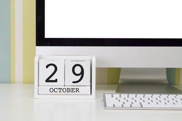 Cube shape calendar for OCTOBER 29 and computer keyboard on table. 