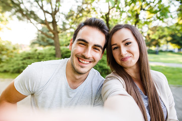 Cute and happy couple enjoying in park and taking selfie
