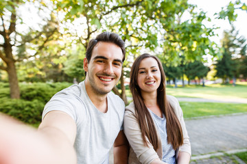 Cute and happy couple enjoying in park and taking selfie