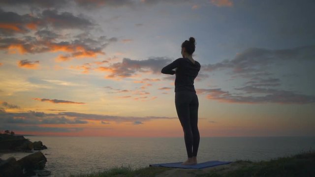 Peaceful beautiful girl doing yoga meditate namaste sunrise coast slow motion