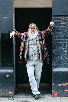 Man with white hair and beard wearing cap backwards