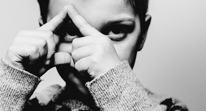 Boy making triangle shape over his eye