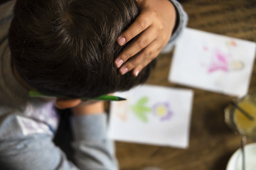 Young kid drawing top view. Hand on the head