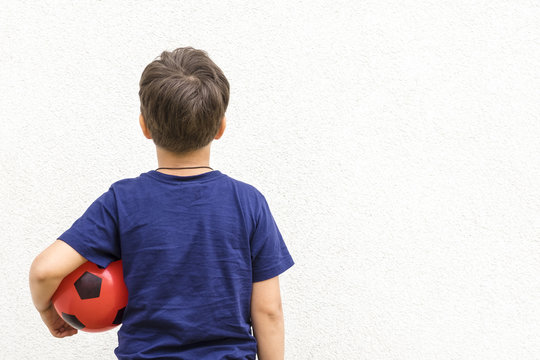 Little Boy In Blue Shirt Holding Red Ball, Back View. Copyspace For Text