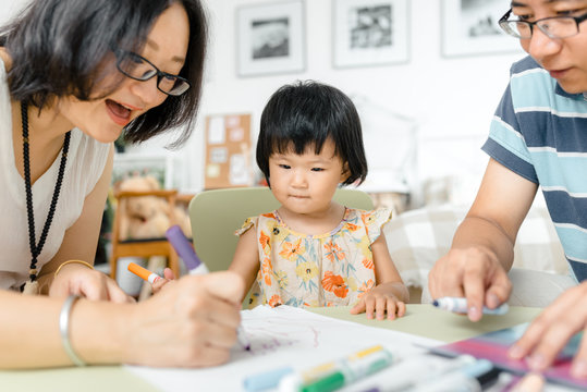 Adorable little girl drawing pictures with her parents
