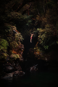 A courageous male jumps from a high cliff into the unknown waters below