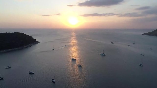Amazing timelaps of tropical sunset under the sea. Yachts in the roadstead timelaps with islands and clouds on horizon. Phuket island.
