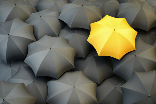 Individuality and difference concept, top view of unique yellow umbrella standing out from the gray crowd