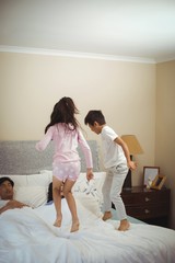 Obraz na płótnie Canvas Siblings jumping on bed in bedroom