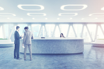 People near a curved office reception, toned