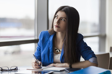 Obraz premium Pensive businesswoman writing in notebook