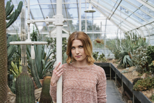 Young woman stands in conservatory