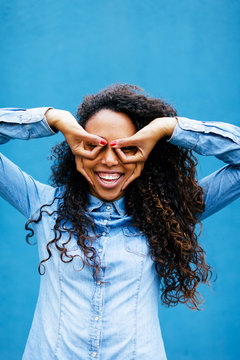 Happy young african woman having fun in front of a blue wall